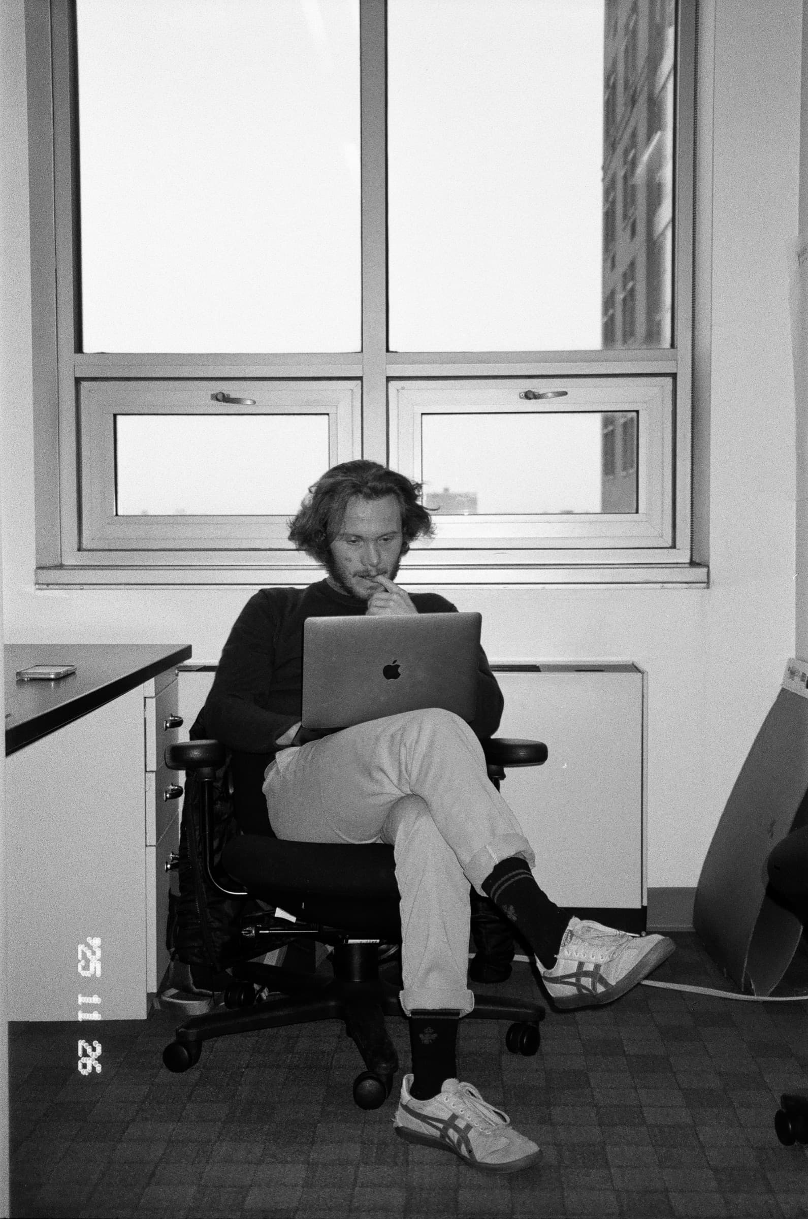 Black and white candid photo of Ethan working on a laptop