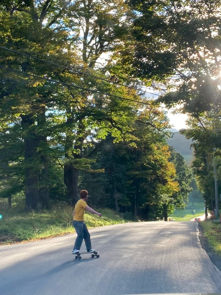 Ethan longboarding down a tree-lined road