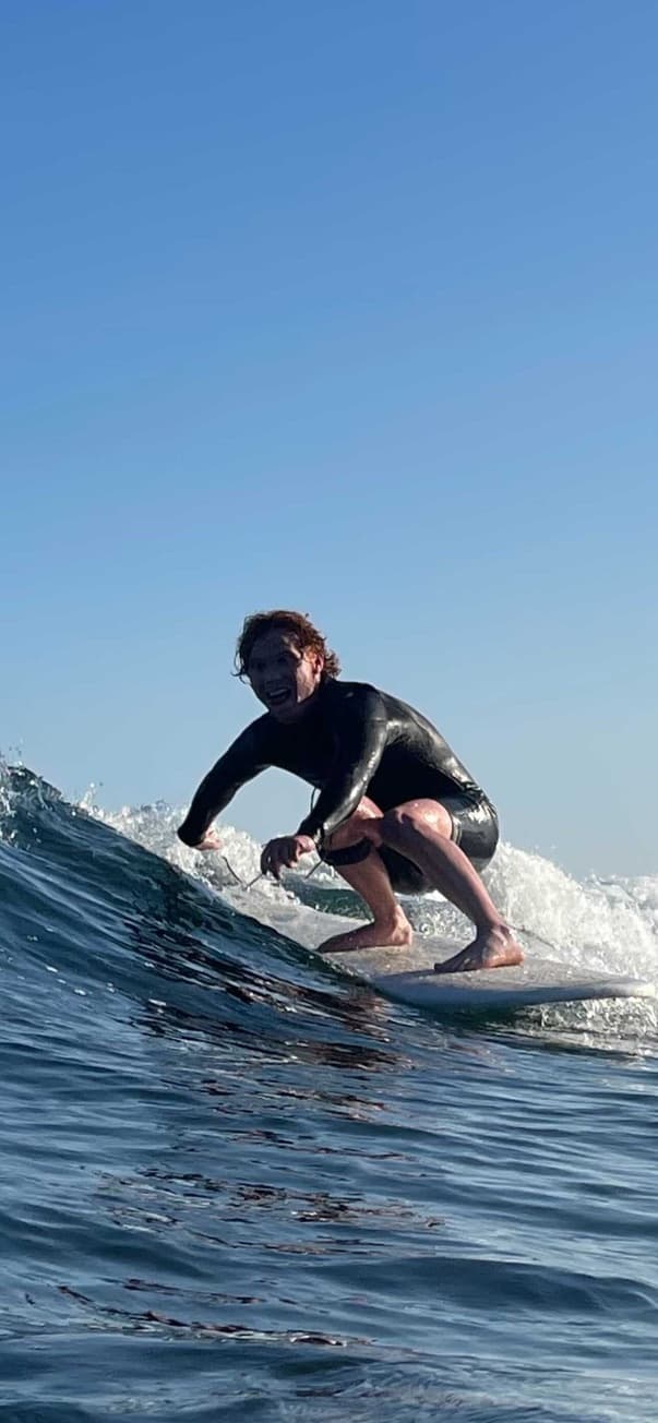 Ethan crouched on a surfboard riding a wave